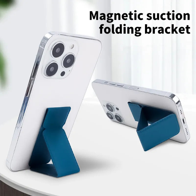 A blue magnetic suction folding phone stand shown holding two white smartphones on a light tabletop, with the text 'Magnetic suction folding bracket' at the top.